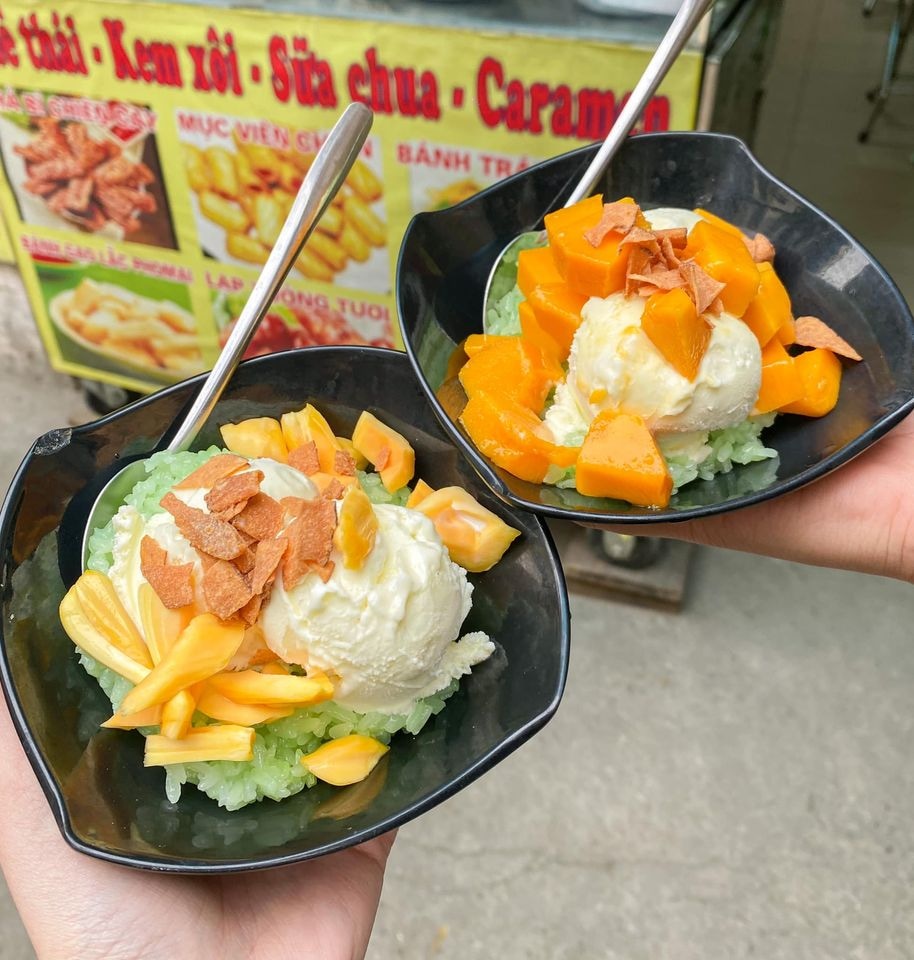 A bowl combining scoops of white coconut ice cream with sticky rice, topped with crushed coconut 